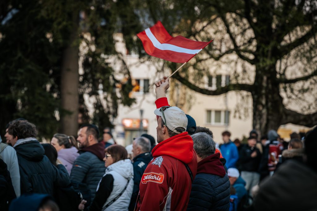 Latvijas hokeja līdzjutējs fanu zonā Valmierā ar sarkanbaltsarkano karogu.
