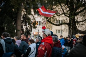 Latvijas hokeja līdzjutējs fanu zonā Valmierā ar sarkanbaltsarkano karogu.
