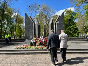 Divi vīrieši ar ziediem tuvojas ziediem klātai piemiņas vietai Daugavpilī 9. maijā.