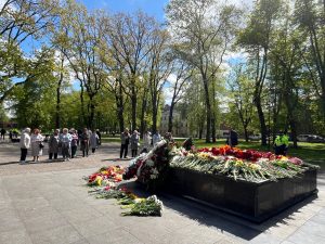 Cilvēku grupa pulcējusies pie ziediem klātas piemiņas vietas Daugavpilī 9. maijā