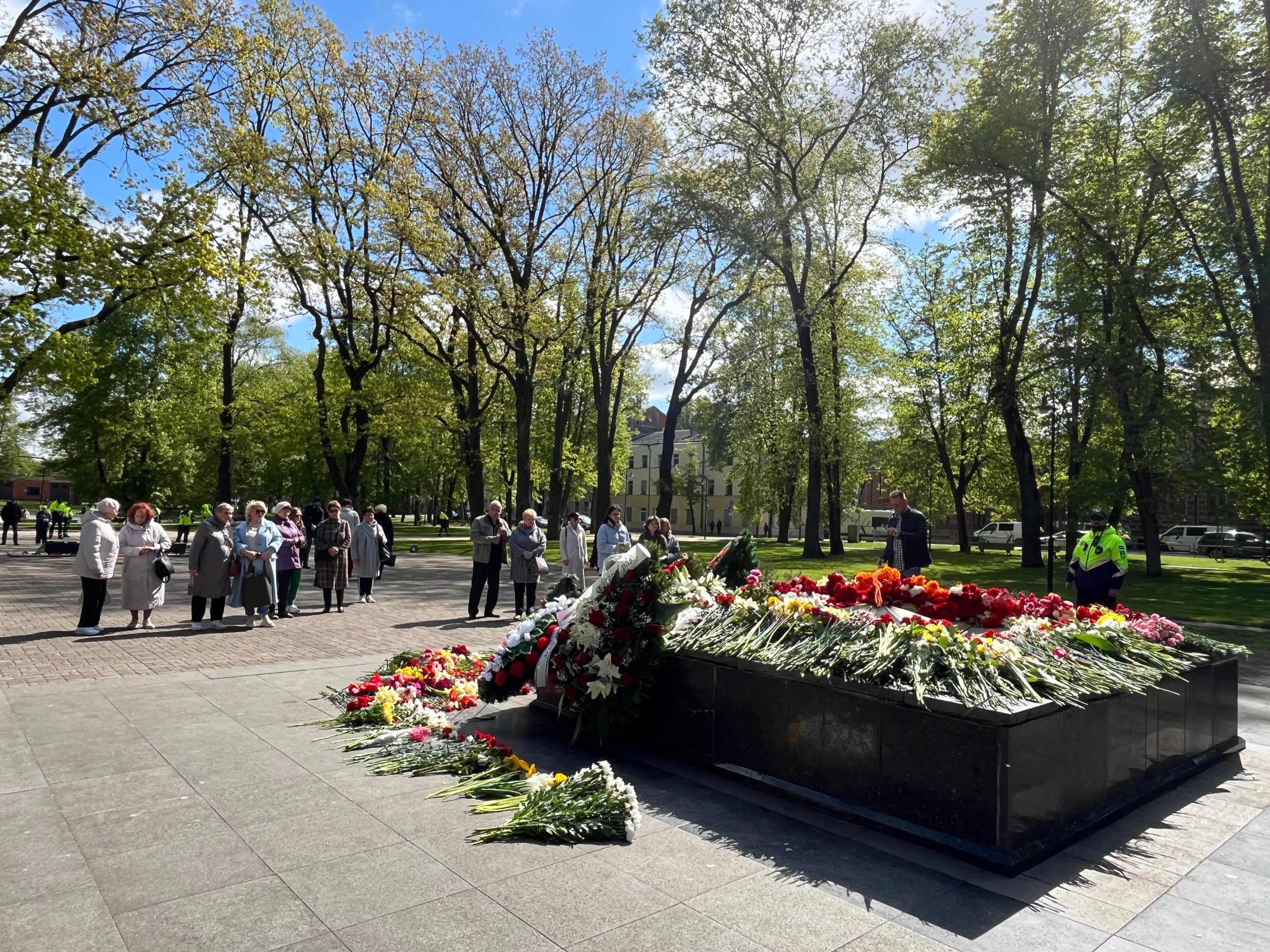 Cilvēku grupa pulcējusies pie ziediem klātas piemiņas vietas Daugavpilī 9. maijā