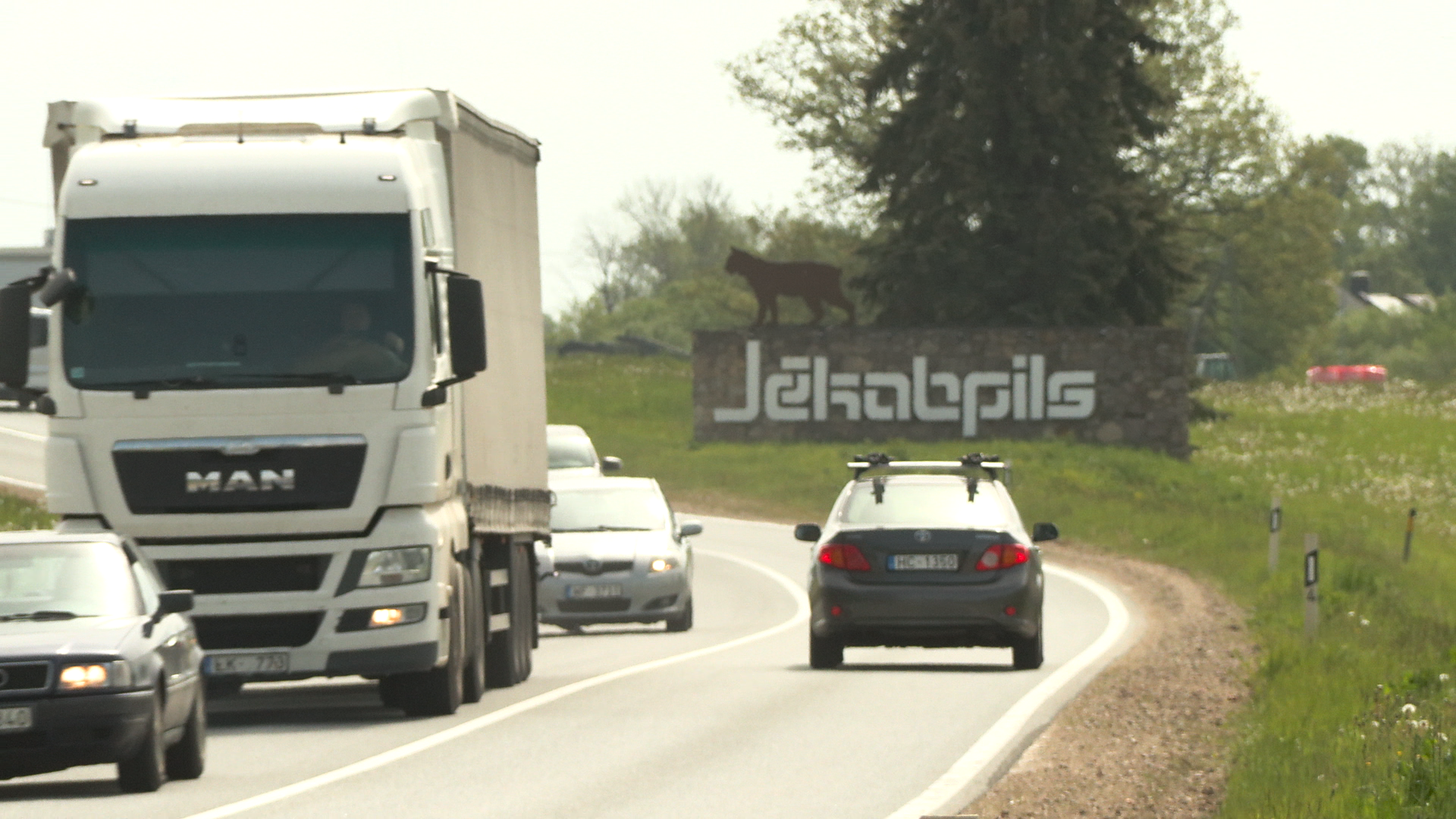 Automašīnas iebrauc Jēkabpilī, redzama pilsētas zīme ar lūsi