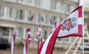 Latvijas karogs ar valsts ģerboni pie ēkas Aizkrauklē