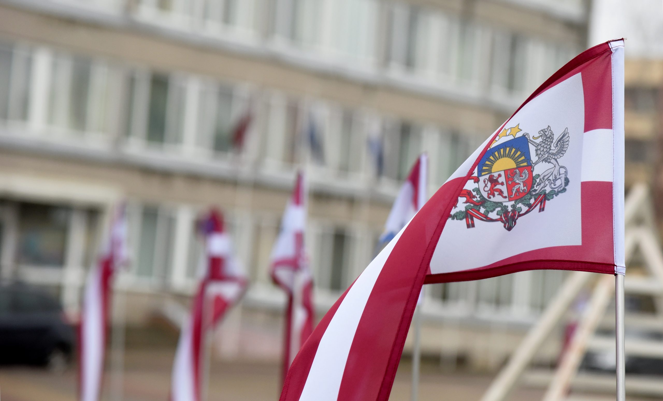 Latvijas karogs ar valsts ģerboni pie ēkas Aizkrauklē
