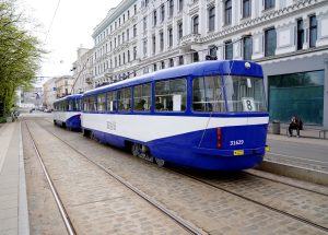 Zili-balts tramvajs ar numuru 8 un 31629 stāv uz sliedēm Rīgas centrā, gar ielu ar vecpilsētas arhitektūru