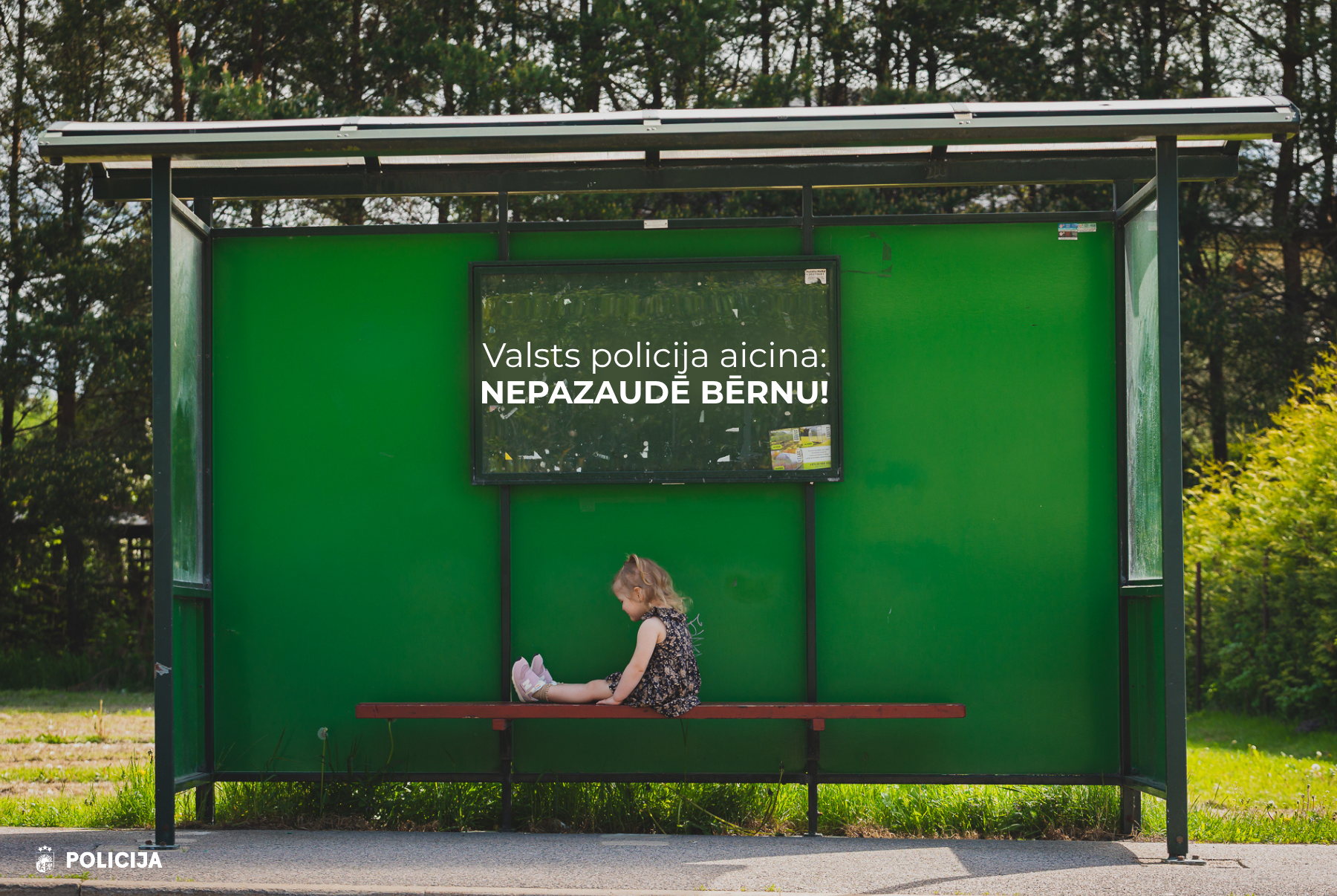 Mazs bērns viens pats pieturā ar uzrakstu “Valsts policija aicina: Nepazaudē bērnu!”