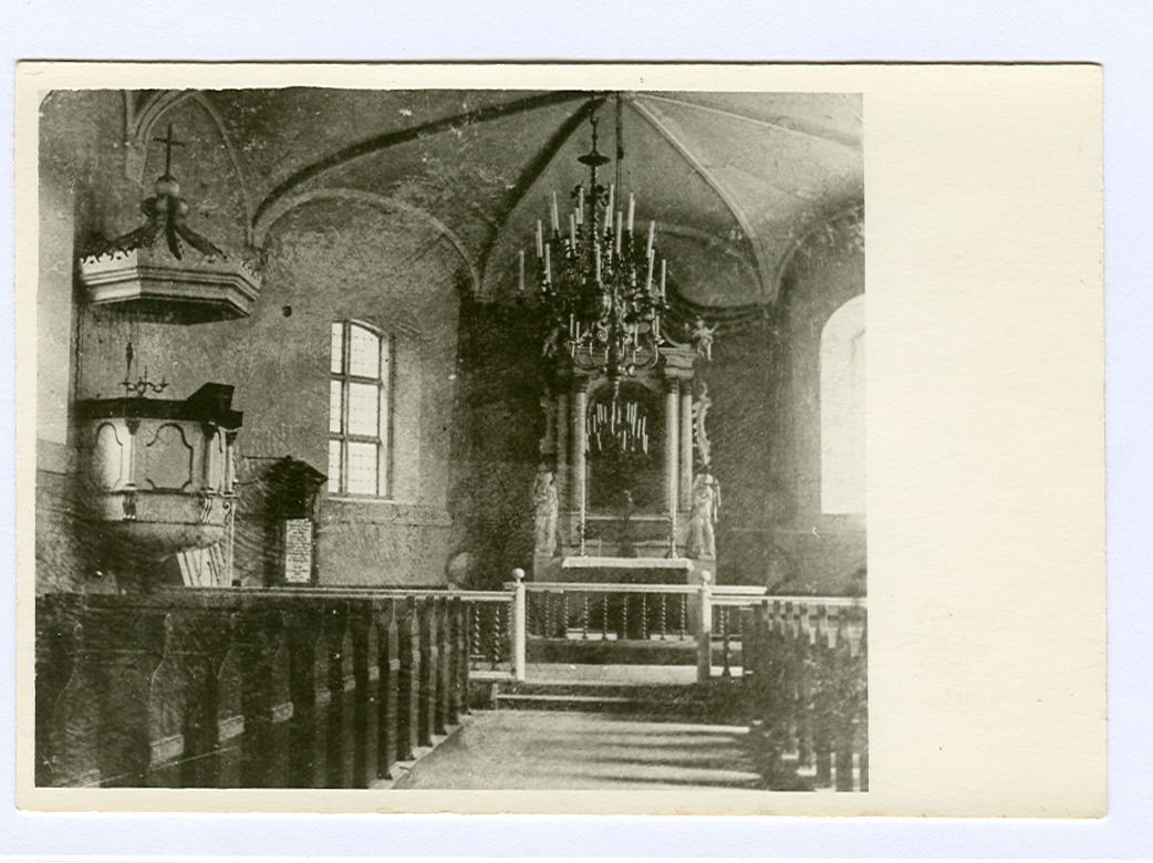 Melnbalta fotogrāfija ar Mālpils baznīcas iekšskatu, redzams altāris, kancele un soli