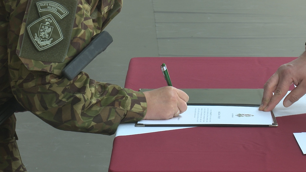 Valsts robežsardzes koledžas kadets paraksta zvēresta dokumentu pie Latvijas karoga