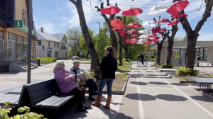 Ogres iedzīvotājas sarunājas uz ielas zem sarkanbaltiem lietussargiem pirms vēlēšanām