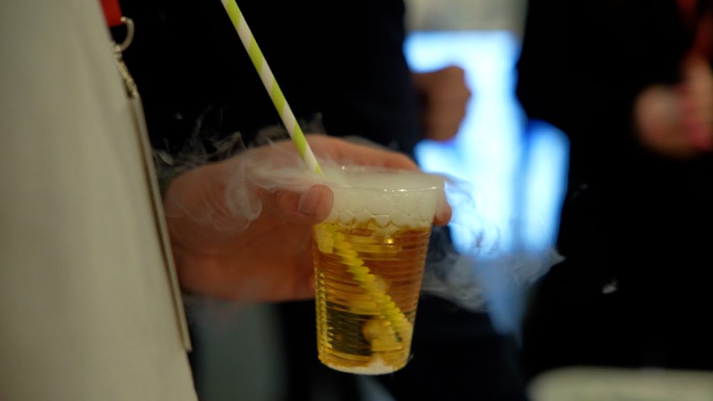 Cilvēka roka tur plastmasas glāzi ar šķidrumu un tvaiku