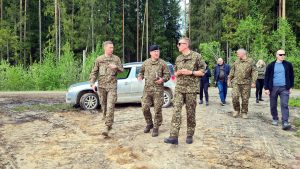 Valsts prezidents Edgars Rinkēvičs un militārpersonas iet pa dubļainu ceļu Sēlijas militārajā poligonā
