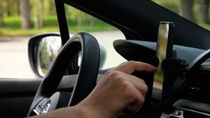 Vadītājs izmanto viedtālruni turētājā automašīnā