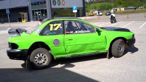 Zaļš sacīkšu auto ar numuru 17 stāv stāvlaukumā pie ēkas