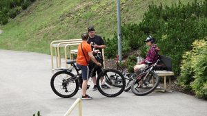 Pusaudži ar velosipēdiem sēž un sarunājas parkā