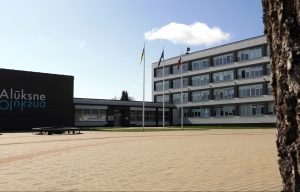 Alūksnes novada pašvaldības ēka ar karogiem priekšplānā
