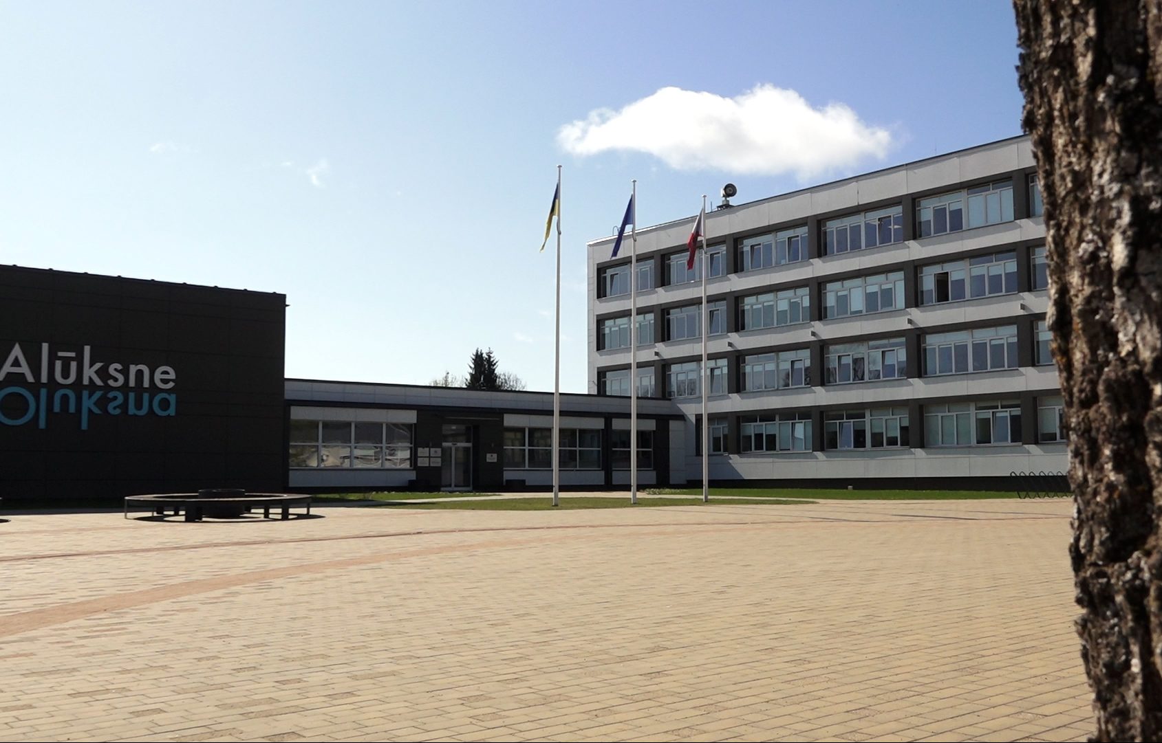 Alūksnes novada pašvaldības ēka ar karogiem priekšplānā