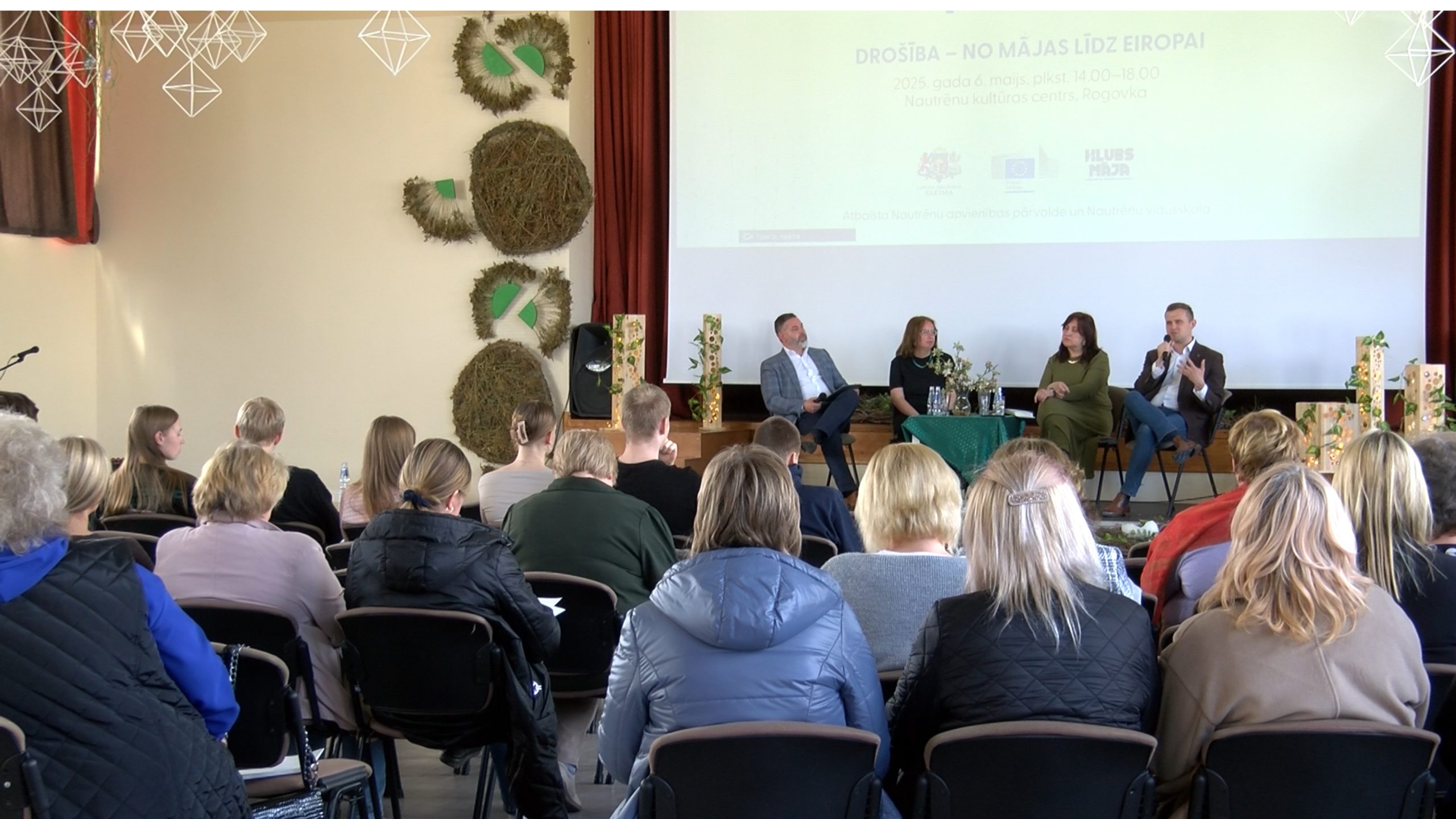 Skats no aizmugures uz auditoriju, kas klausās paneļdiskusiju par drošību
