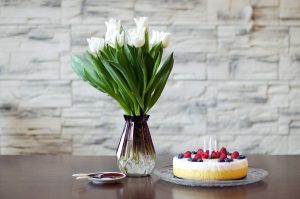 Dzimšanas dienas kūka ar svecītēm un baltas tulipes stikla vāzē