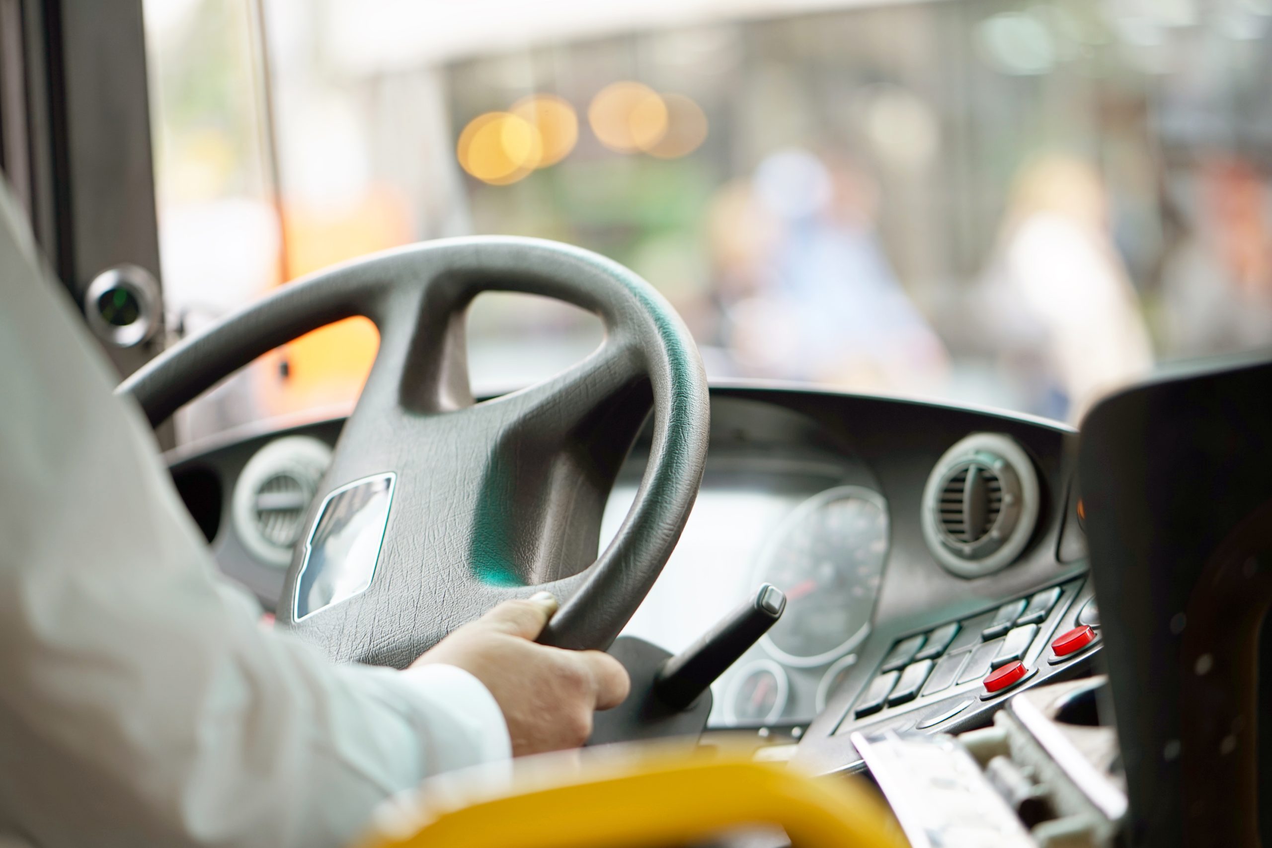 Sabiedriskā autobusa vadītājs tur stūri pie vadības paneļa