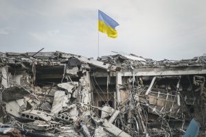 Ukrainas karogs plīvo virs sagrautas ēkas drupām