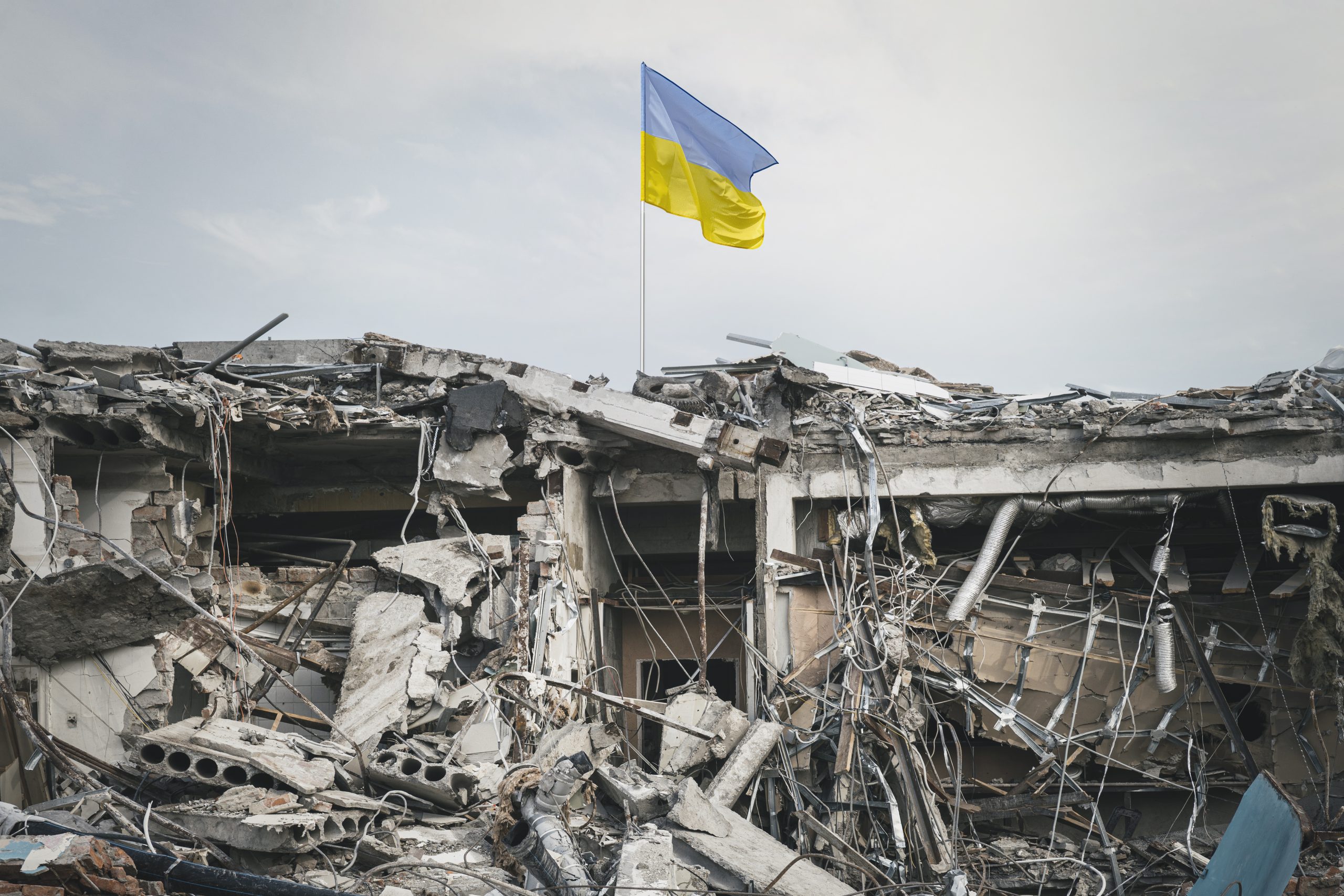 Ukrainas karogs plīvo virs sagrautas ēkas drupām