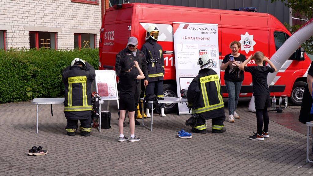 Bērni un pieaugušie piedalās interaktīvās drošības apmācībās pie ugunsdzēsēju mašīnas Talsu 2. vidusskolas "Drošības dienā"