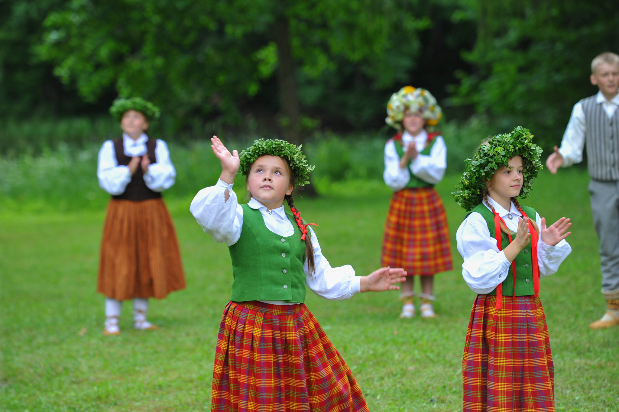 Bērni latviešu tautastērpos ar vainagiem galvās