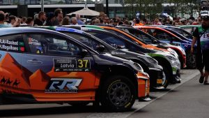 Rallija auto rinda ar skatītājiem fonā pirms sacensību sākuma Latvijā