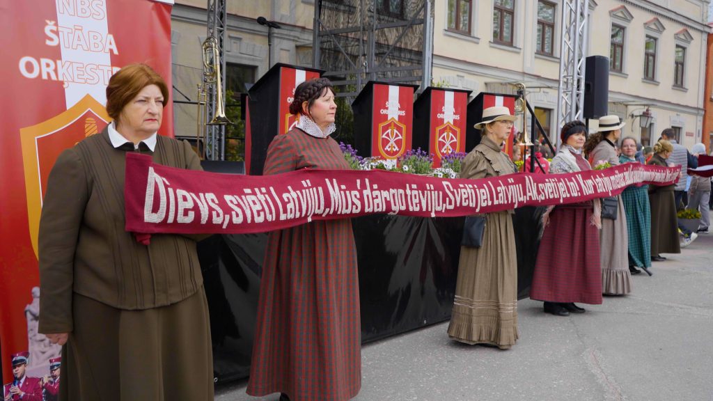 Sievietes tautas tērpos tur izšūtu jostu ar Latvijas himnas vārdiem
