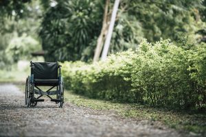 Tukšs ratiņkrēsls uz grants ceļa zaļā parkā