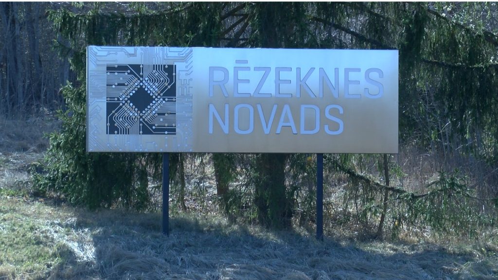 Metāla izkārtne ar uzrakstu "Rēzeknes novads" un mikroshēmas attēlu