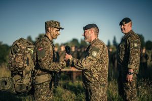 Latvijas karavīrs saņem militāro cepuri no virsnieka lauka apmācību noslēgumā