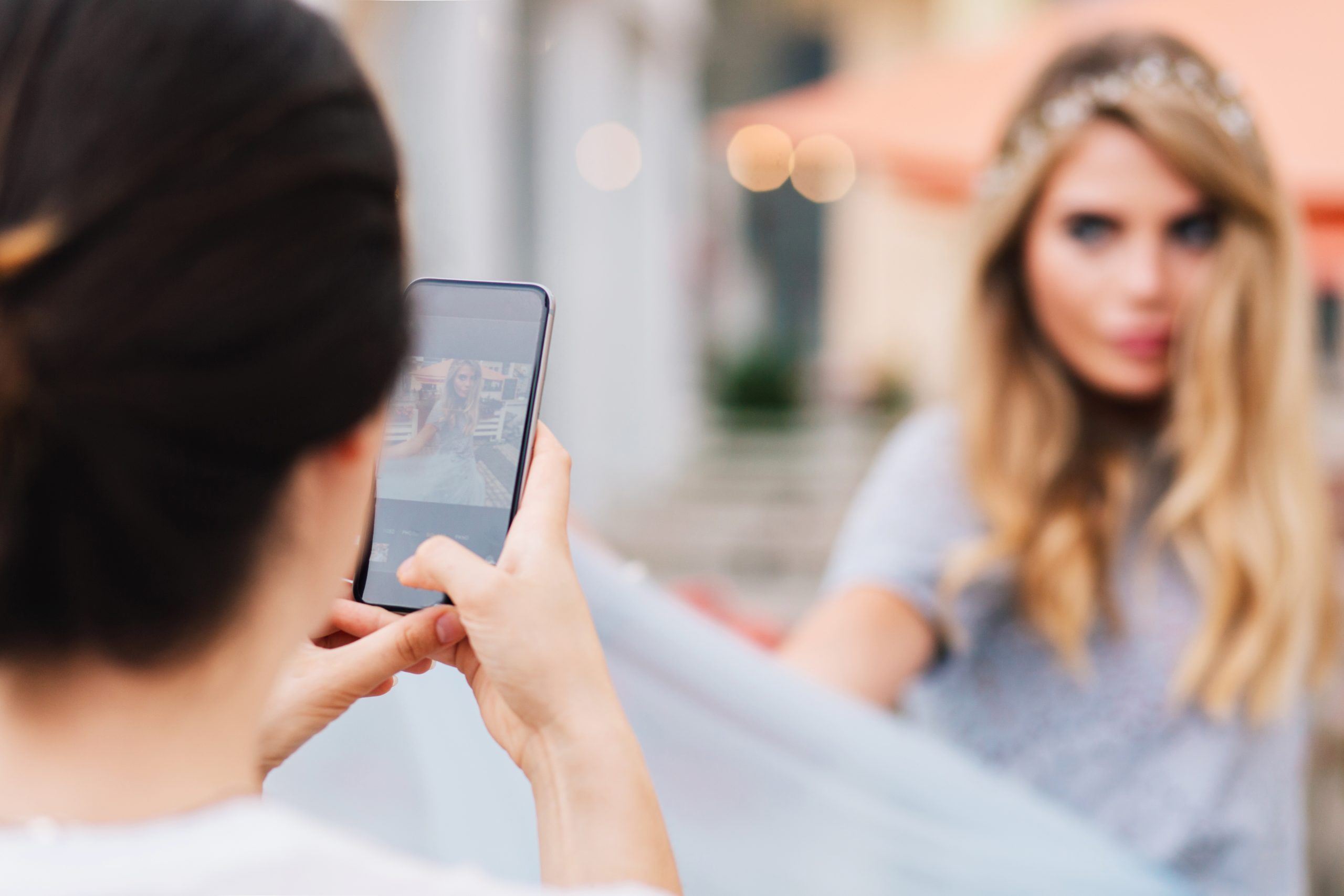 Persona fotografē citu personu ar viedtālruni, uzņemot attēlu sociālajiem medijiem
