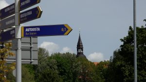 Norādes ceļazīme Valmierā ar baznīcas torni fonā