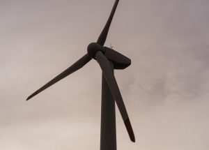 Vēja turbīna pret blāvu, mākoņainu debesu fonu saulrietā
