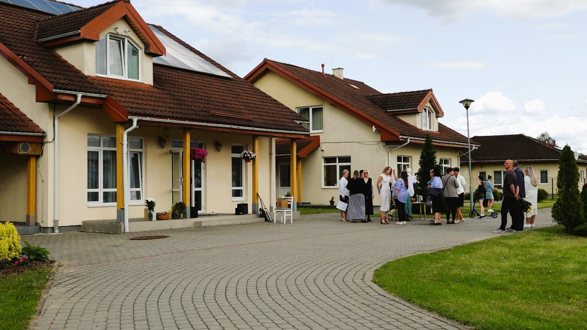 Valmieras SOS bērnu ciemata ēkas un pagalms ar cilvēku grupu
