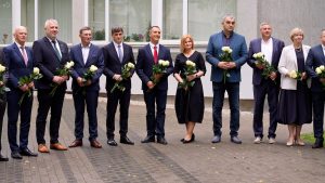Talsu novada domes deputāti stāv rindā ar baltām rozēm rokās