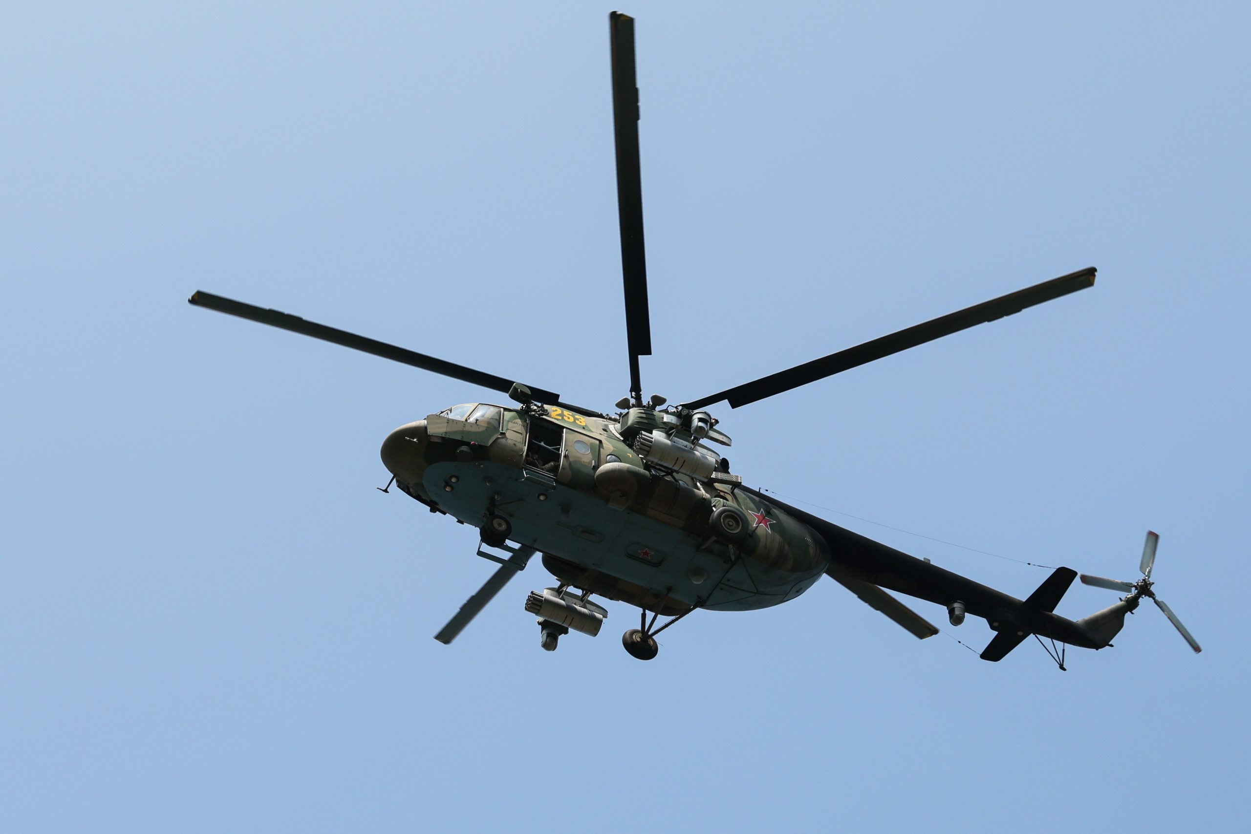 Militārs helikopters lido debesīs ar redzamu Krievijas zvaigznes simboliku