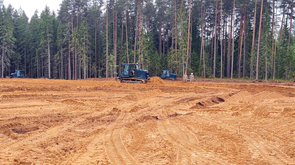 Zemes līdzināšanas darbi Sēlijas militārajā poligonā, redzami buldozeri un karavīri meža fonā