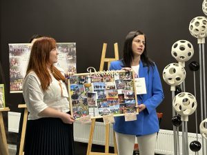 Divas sievietes prezentē kopienas aktivitāšu kolāžu Latvijas Lauku kopienu parlamentā.