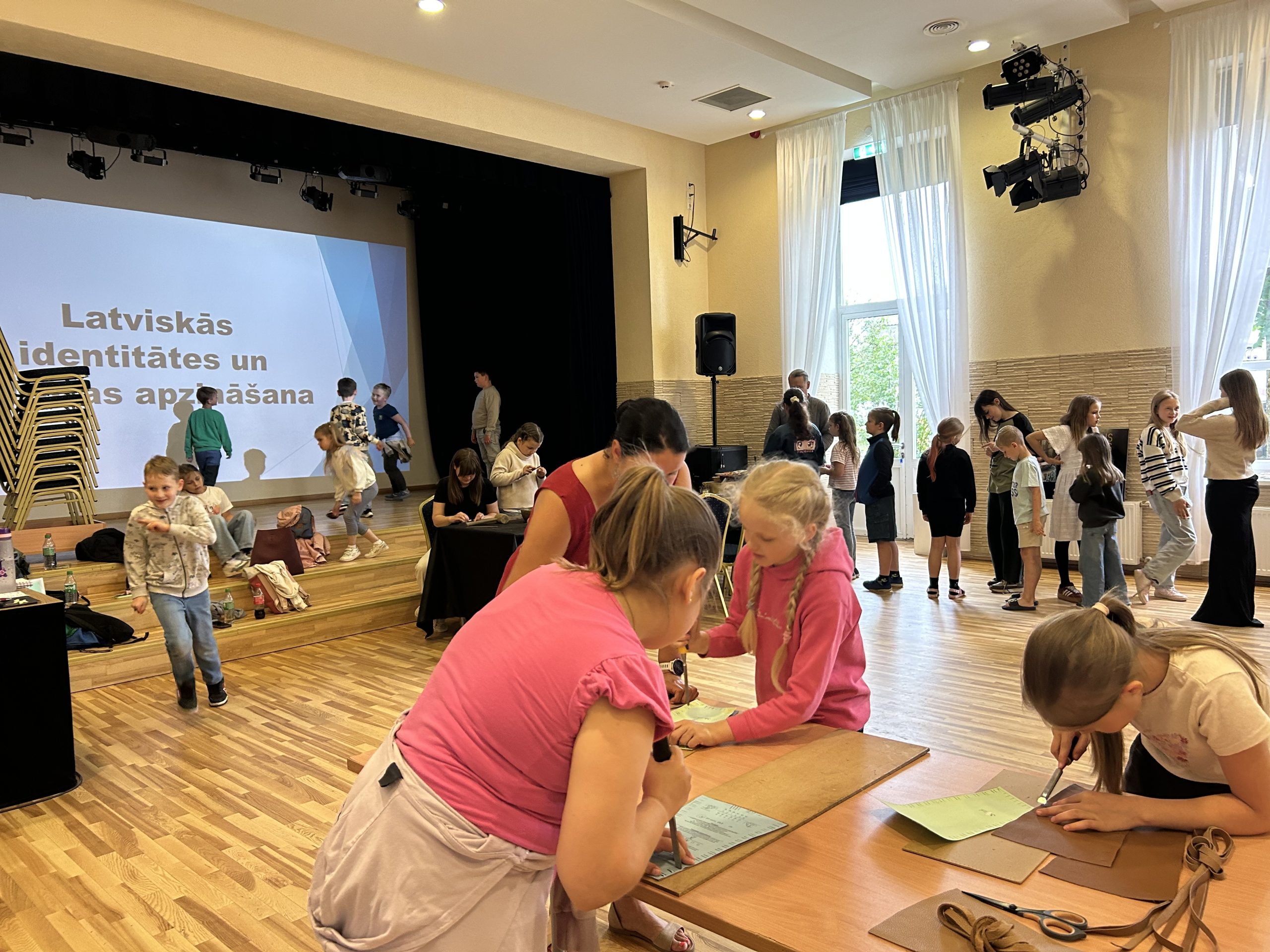 Pasākuma "Latviskās identitātes un kultūras apzināšana" dalībnieki, ieskaitot bērnus, iesaistās aktivitātēs