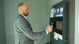 Vīrietis pie taras automāta skenē QR kodu ar dPays lietotni