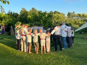 Cilvēki, tostarp bērni, sadodas rokās aplī Jāņu svinību laikā