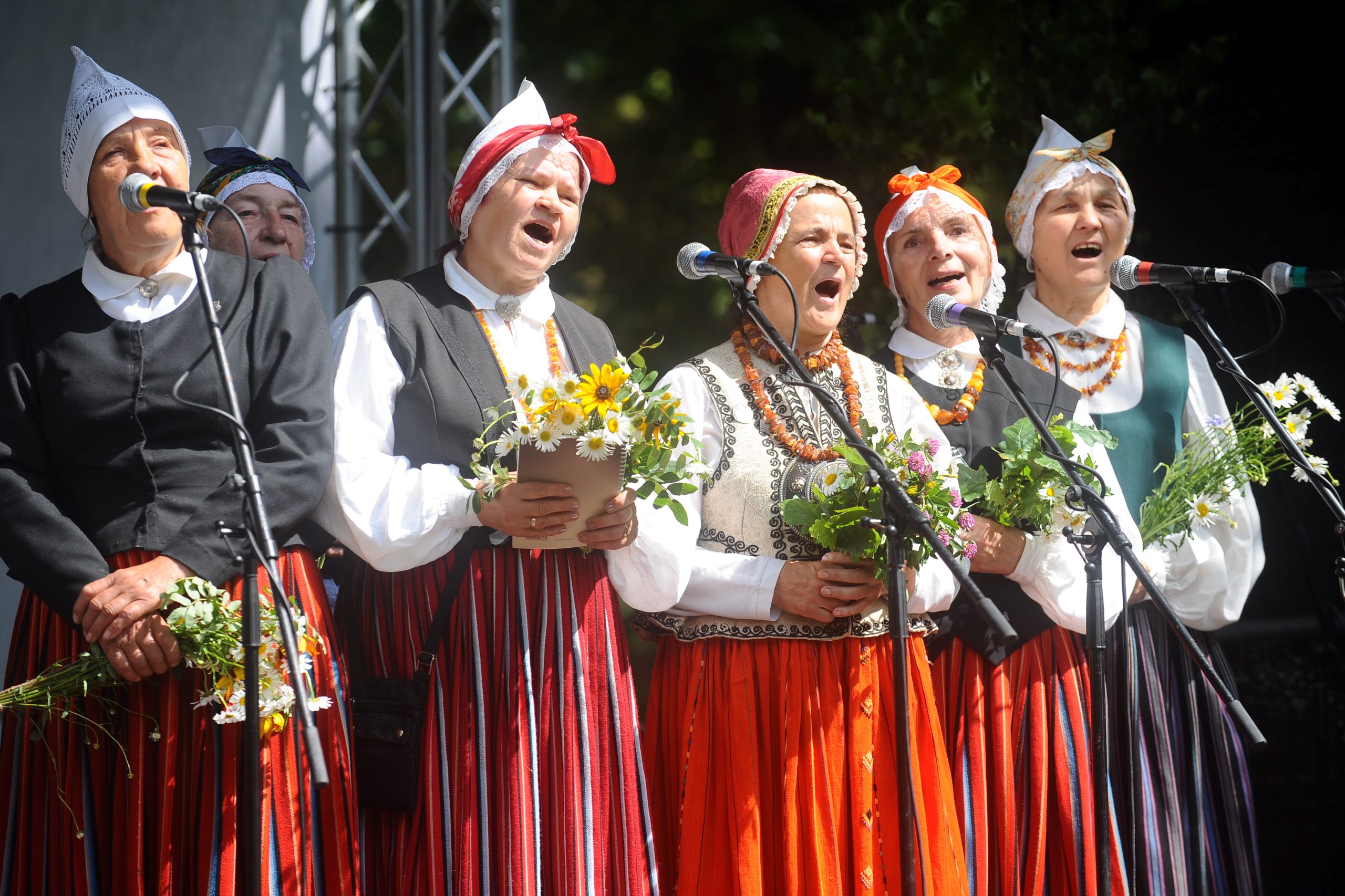 Folkloras kopas dalībnieces tradicionālos tērpos dzied Starptautiskajā folkloras festivālā 
