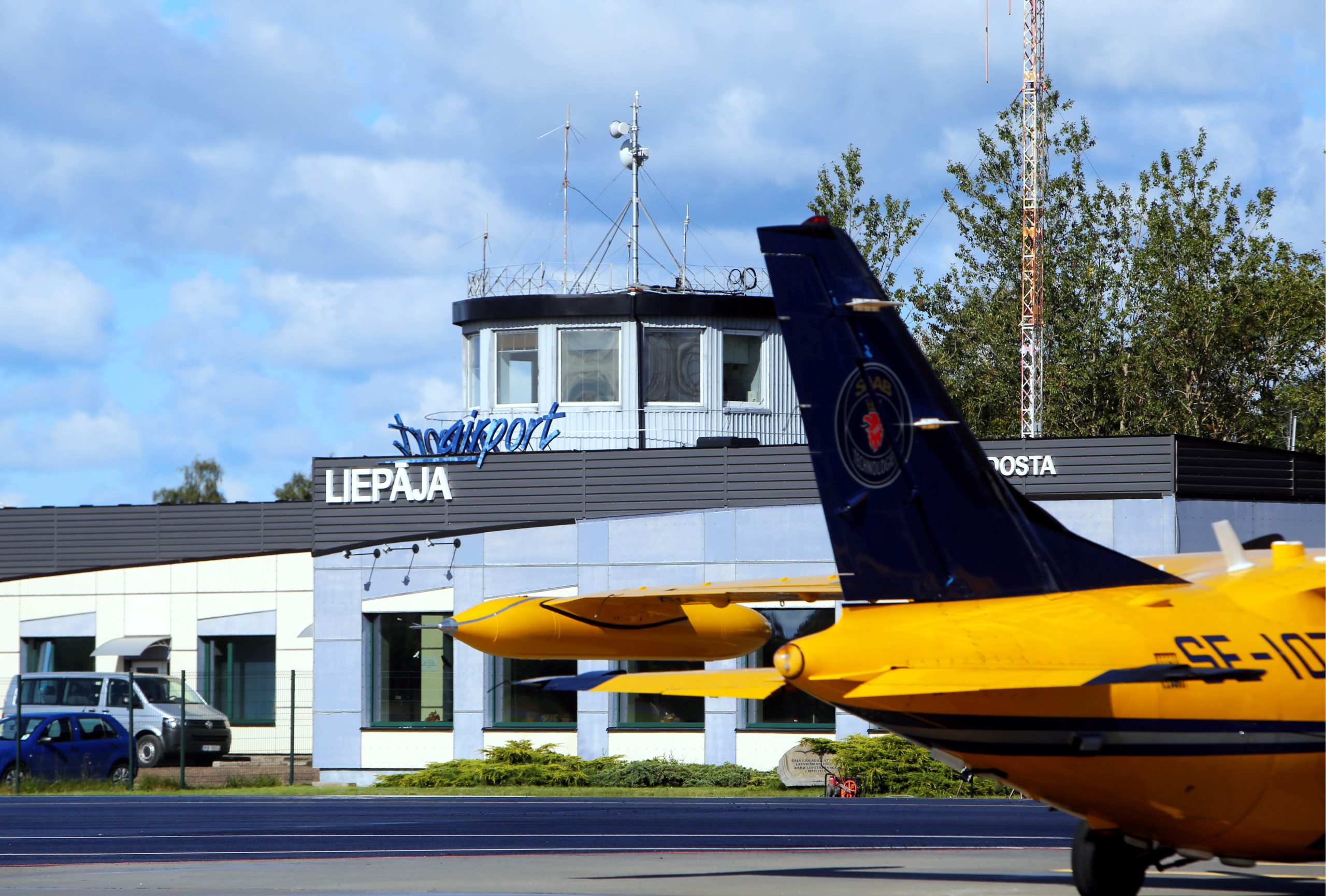 Lidmašīna Liepājas lidostā ar skatu uz vadības torni.