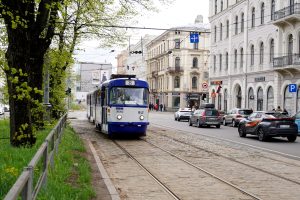 Tramvajs Rīgas ielās pavasarī ar vēsturiskām ēkām fonā