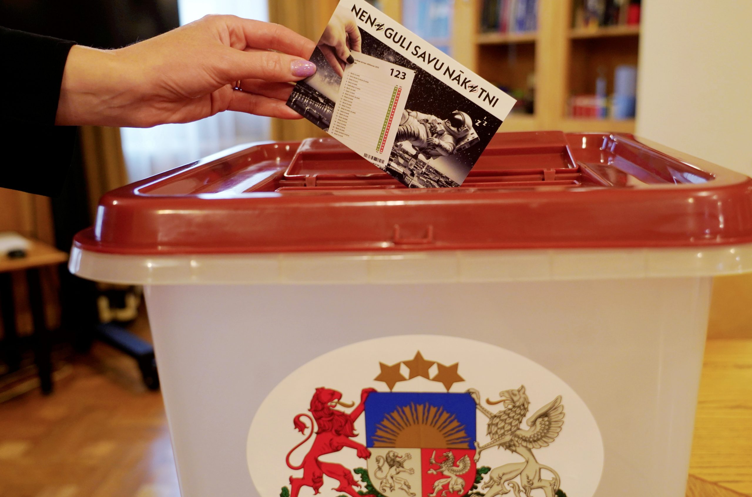 Sieviete iemet vēlēšanu zīmi balsošanas urnā ar uzrakstu “Nenoguli savu nākotni”