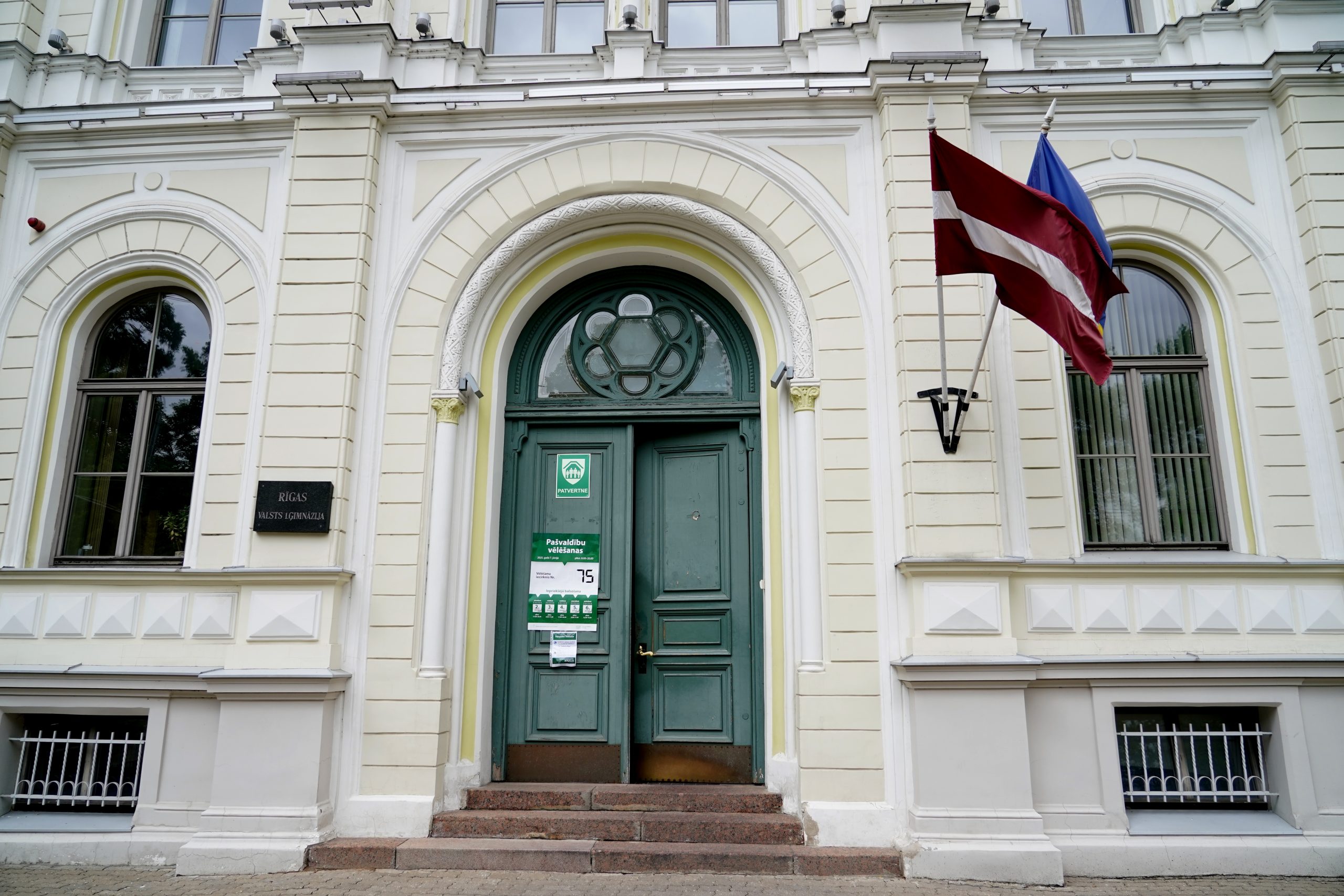 Rīgas Valsts ģimnāzijas ieeja ar vēlēšanu iecirkņa zīmi un Latvijas karogu