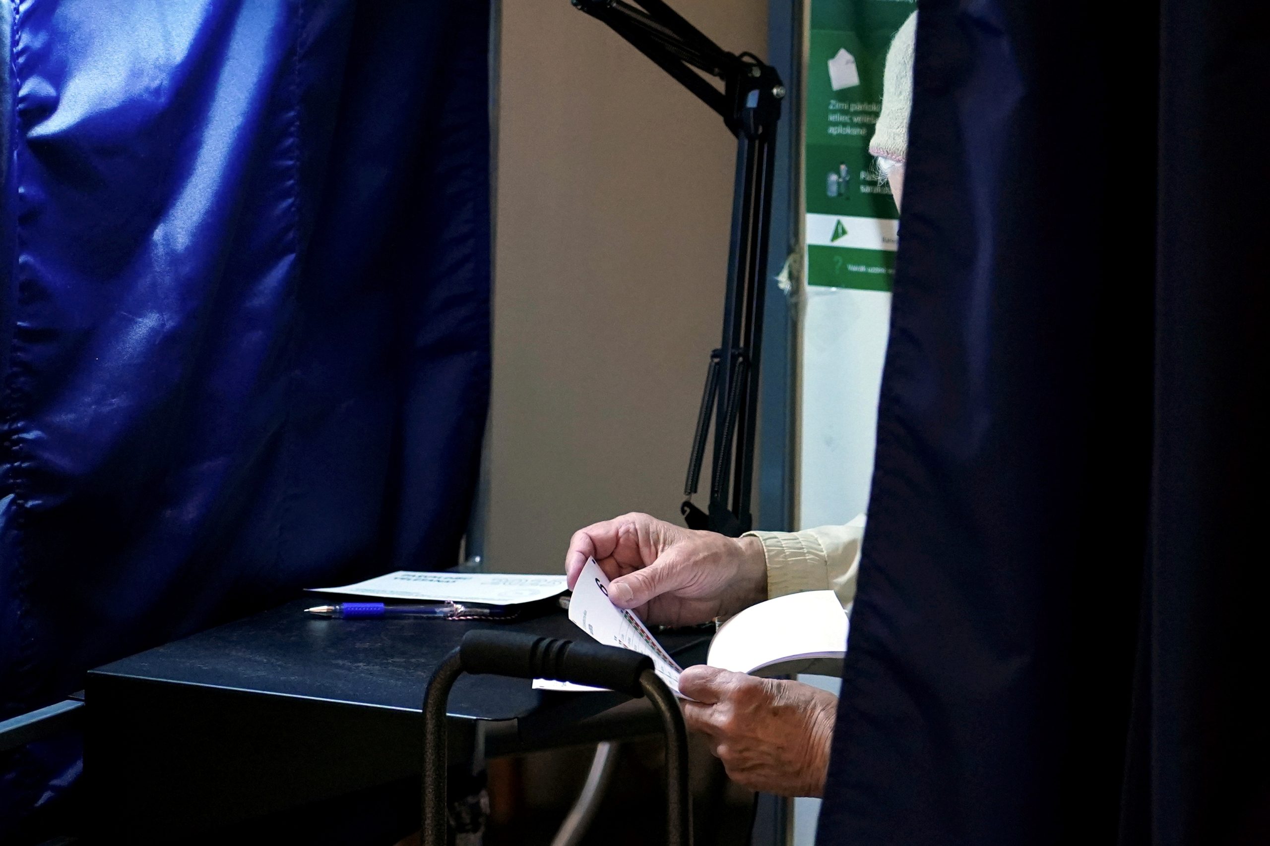 Seniors aizpilda vēlēšanu biļetenu vēlēšanu kabīnē