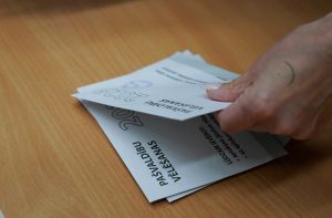 Sievietes roka skaita 2025. gada pašvaldību vēlēšanu aploksnes.